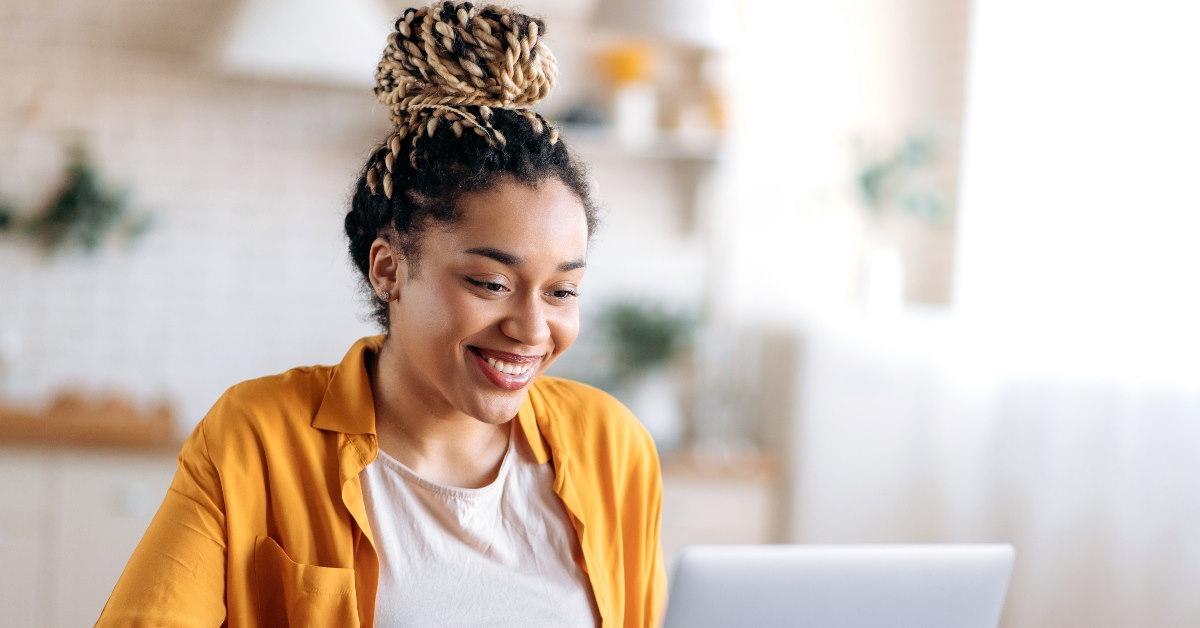 young woman having bun sitting on table working on laptop