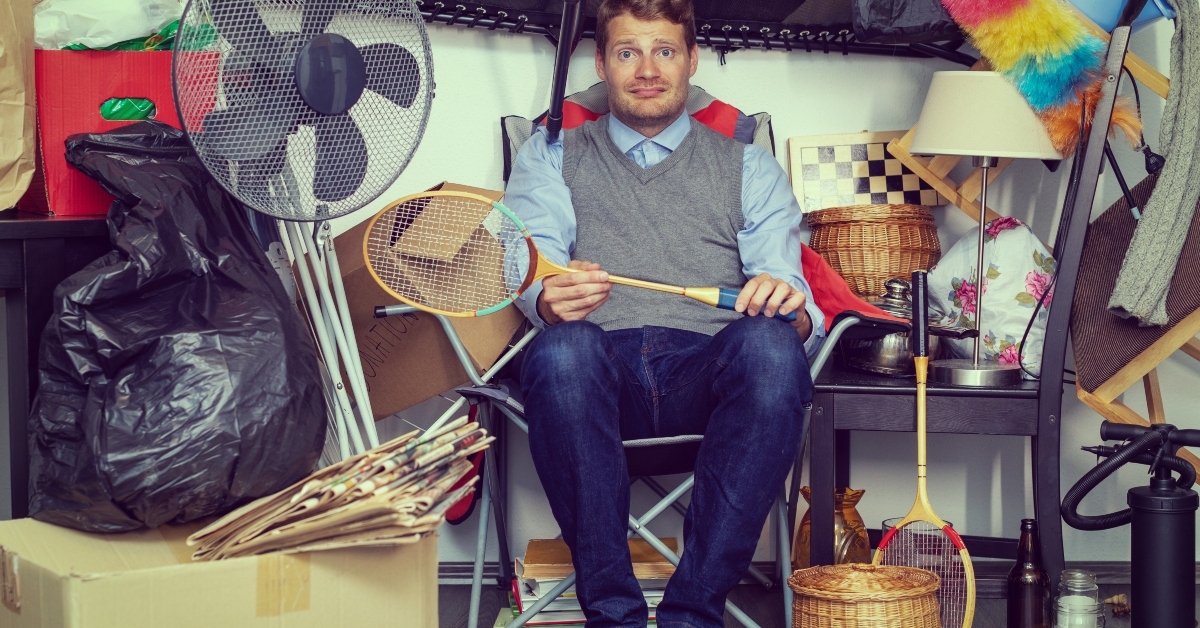 man hoarder with stuff piles sitting in the room