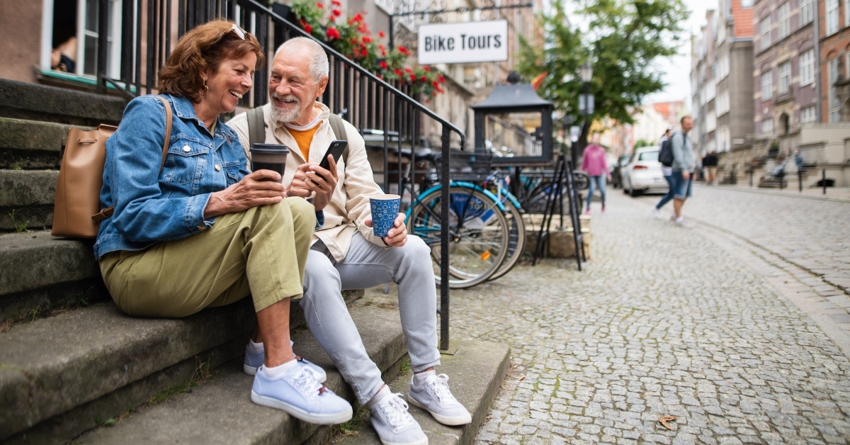 happy senior couple tourists sitting on stairs