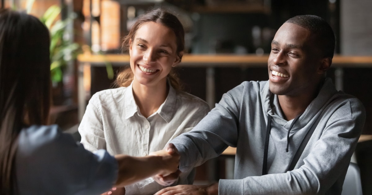 african american man shaking hands with woman across table