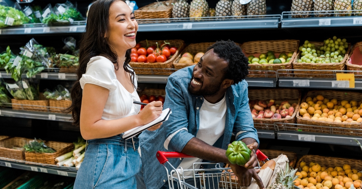 man looking at woman with notebook near shopping cart