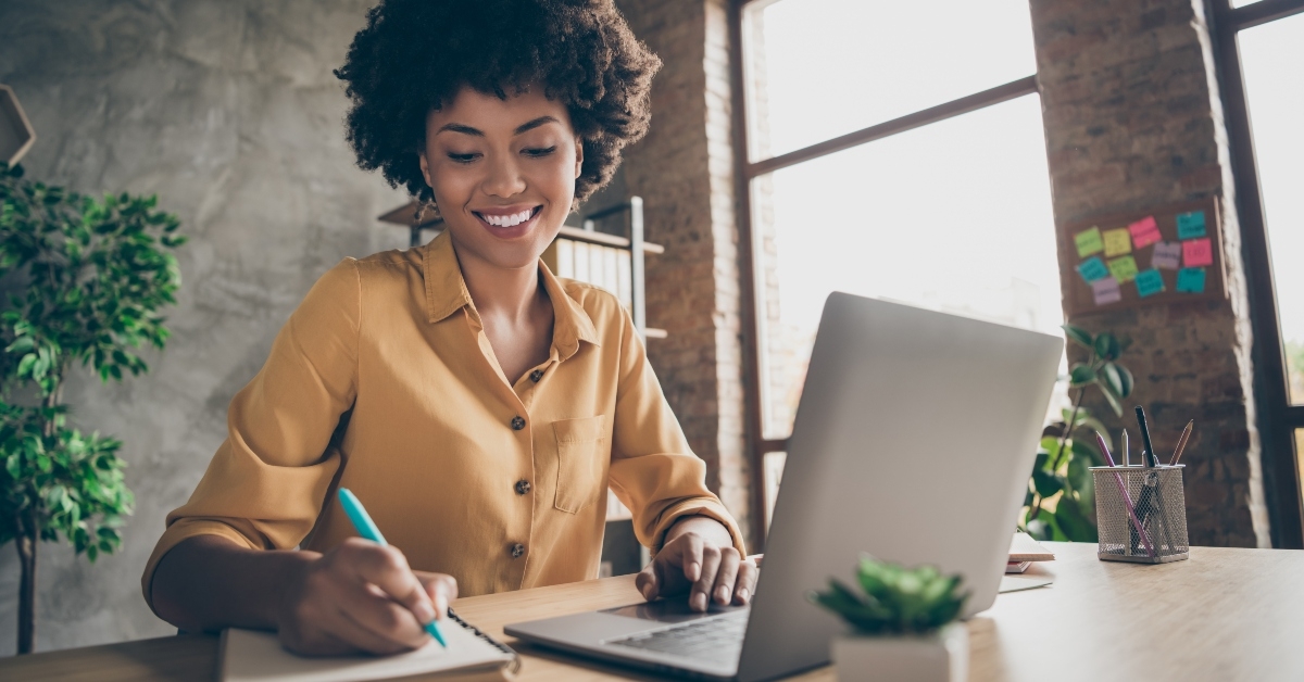 female executive taking down notes infront of laptop