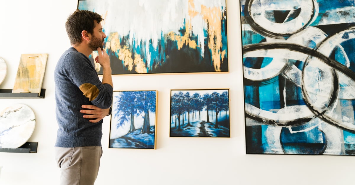 man looking at beautiful paintings in art gallery