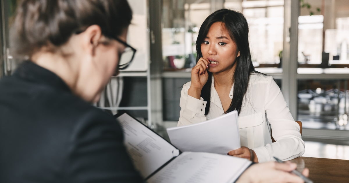 nervous asian woman biting nails in interview 