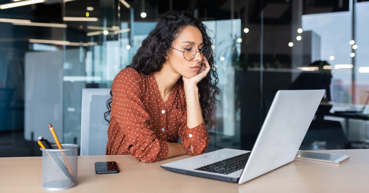 young woman wearing glasses looking at laptop