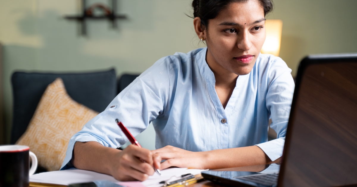 young woman taking notes from laptop 
