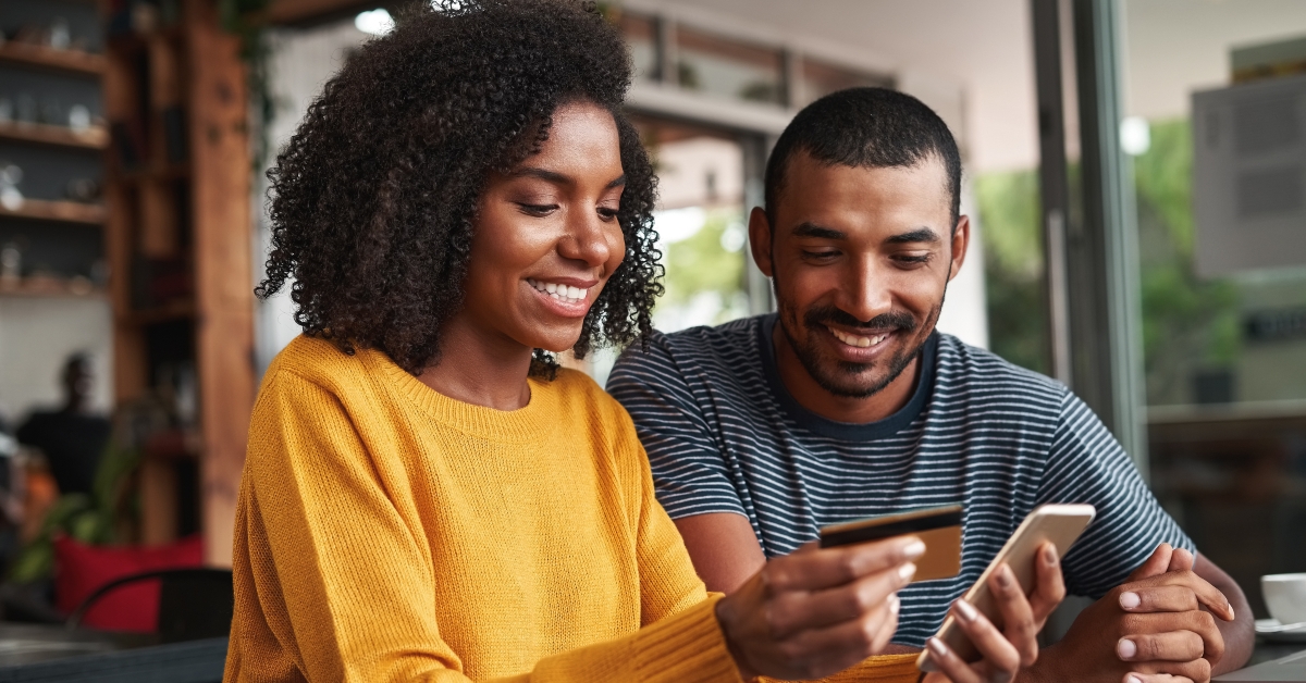 man looking at his girlfriend shopping online in cafe