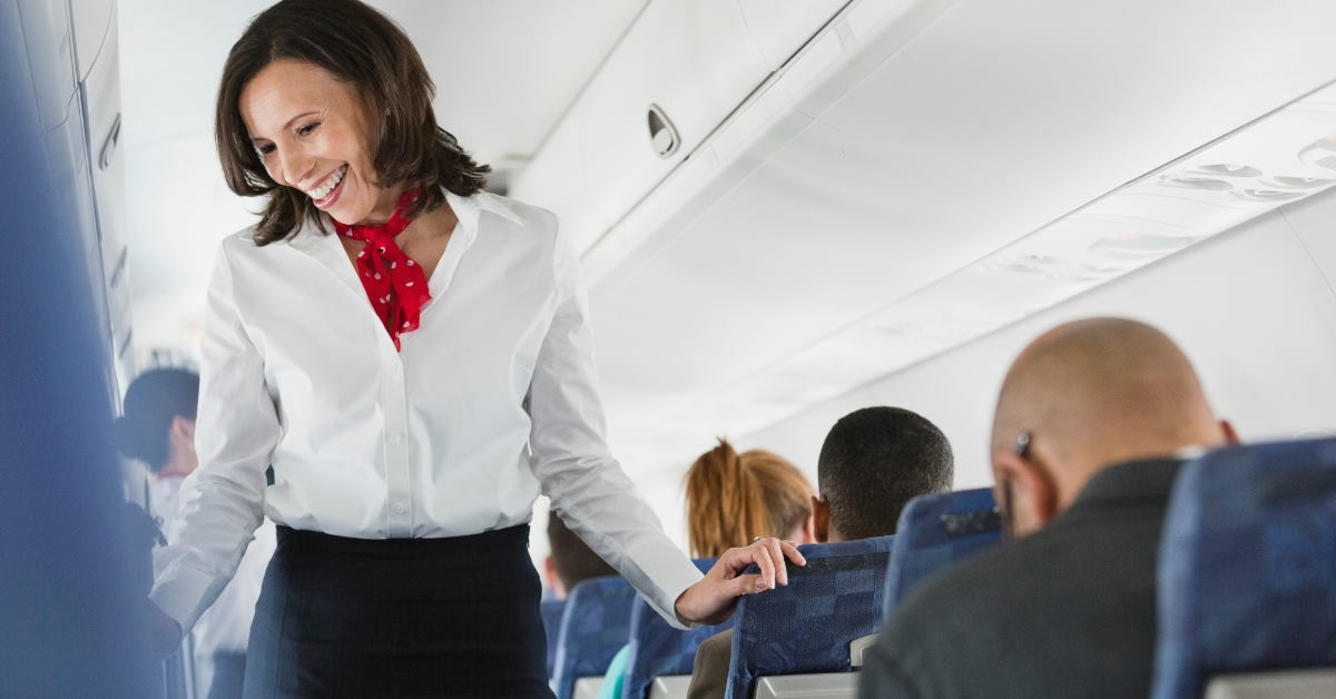 happy flight attendant passing through seats interacting with passengers