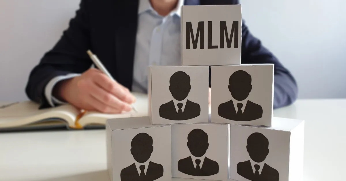 man in the background, sitting on a table and writing in a notebook, with a multi-level marketing pyramid in the foreground