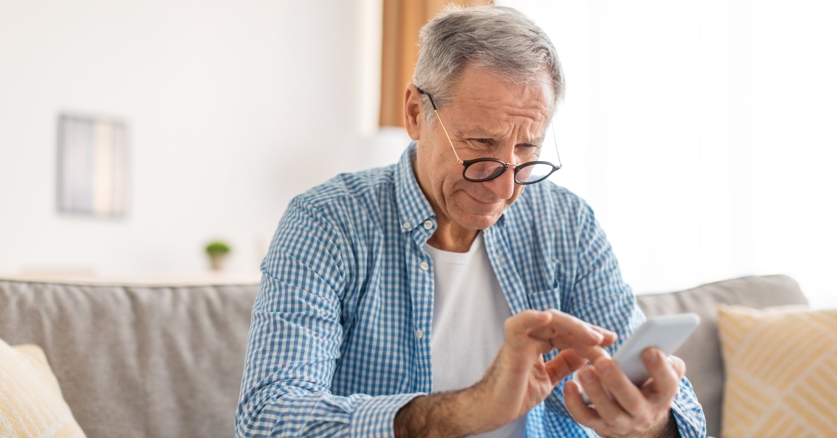 mature man squinting using cell phone