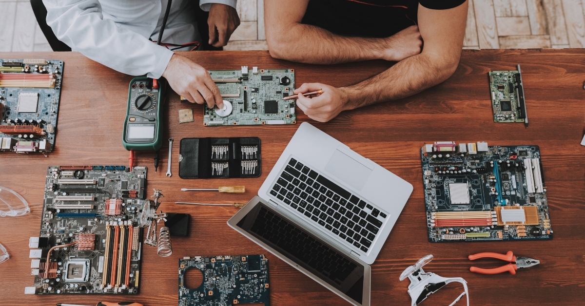 two men with motherboards and tools on wooden table