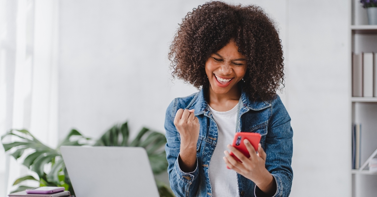 excited african american woman using smartphone 