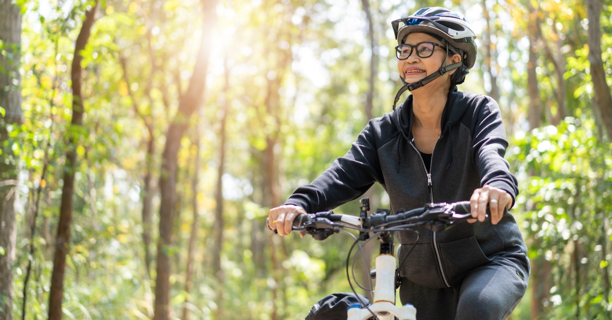 senior asian woman riding bike in park