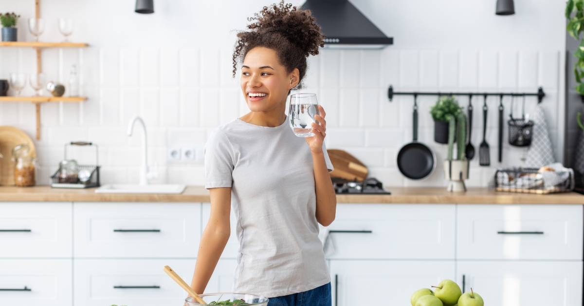 woman cooking healthy food with glass of clean water