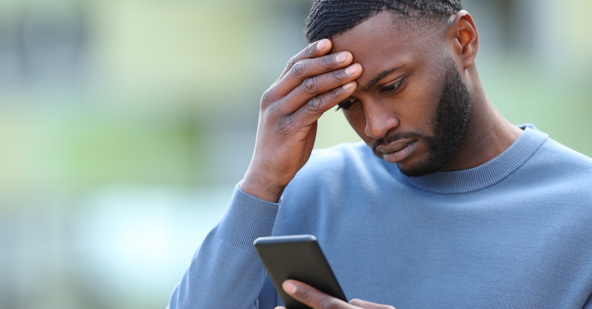 worried black man checking phone in the street