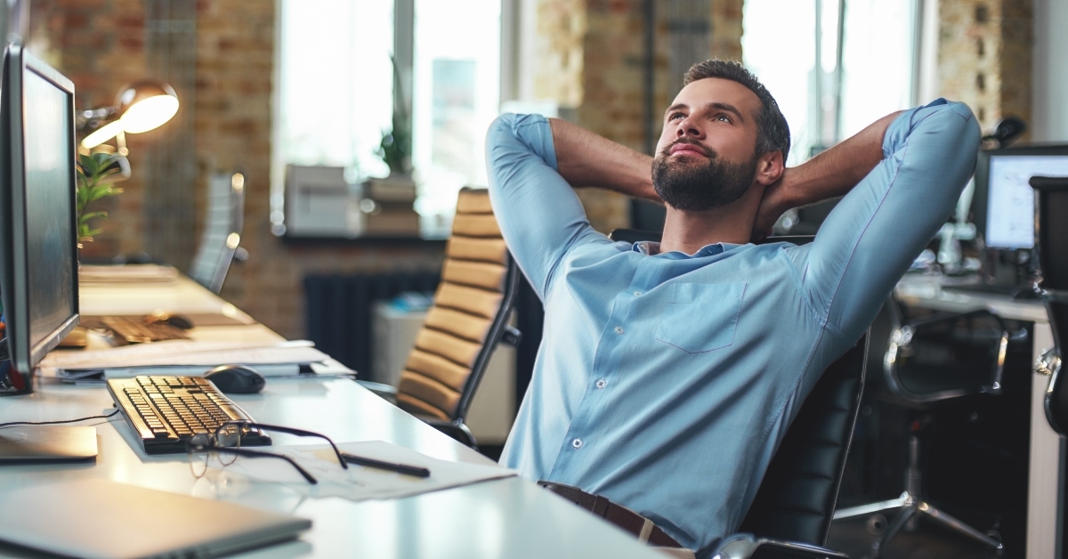 bearded businessman leaning back with hands behind head