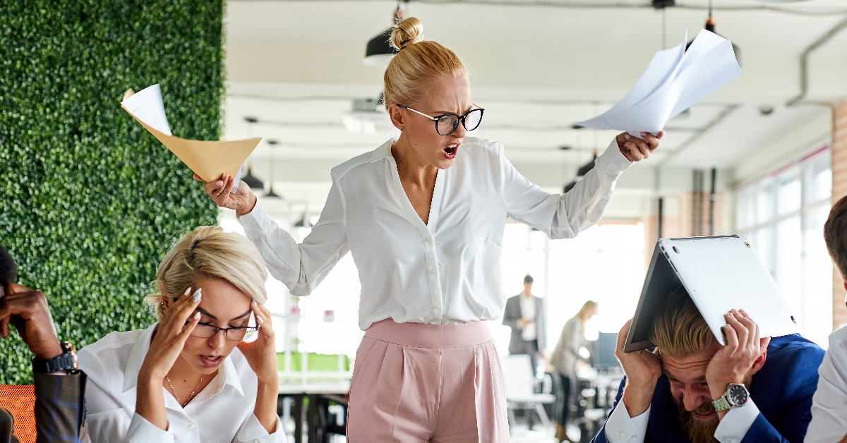 female boss angry at employees holding papers in hands at work