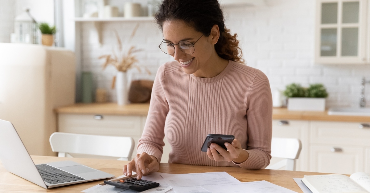 female works with financial papers at home counting on calculator