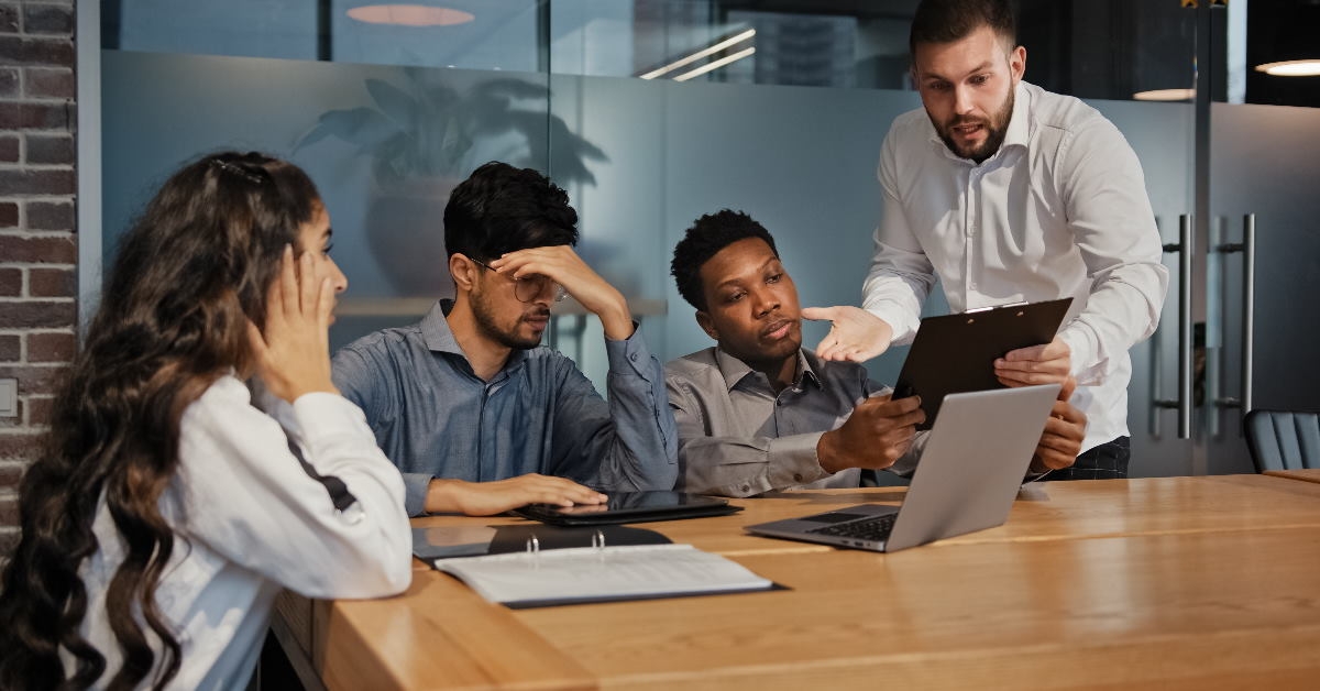 team of colleagues sitting at table having dispute over something at work
