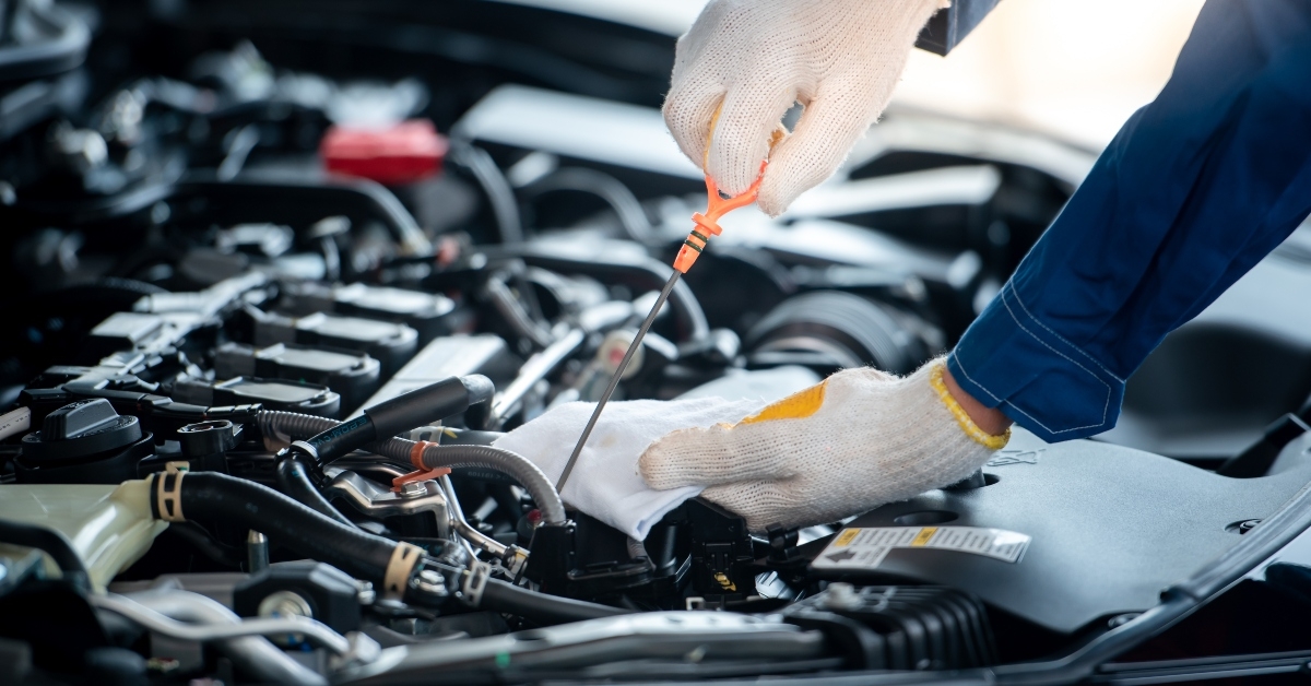 car mechanic in an auto repair shop is checking the engine