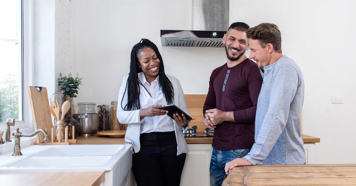 african american real estate agent showing new house to gay couple