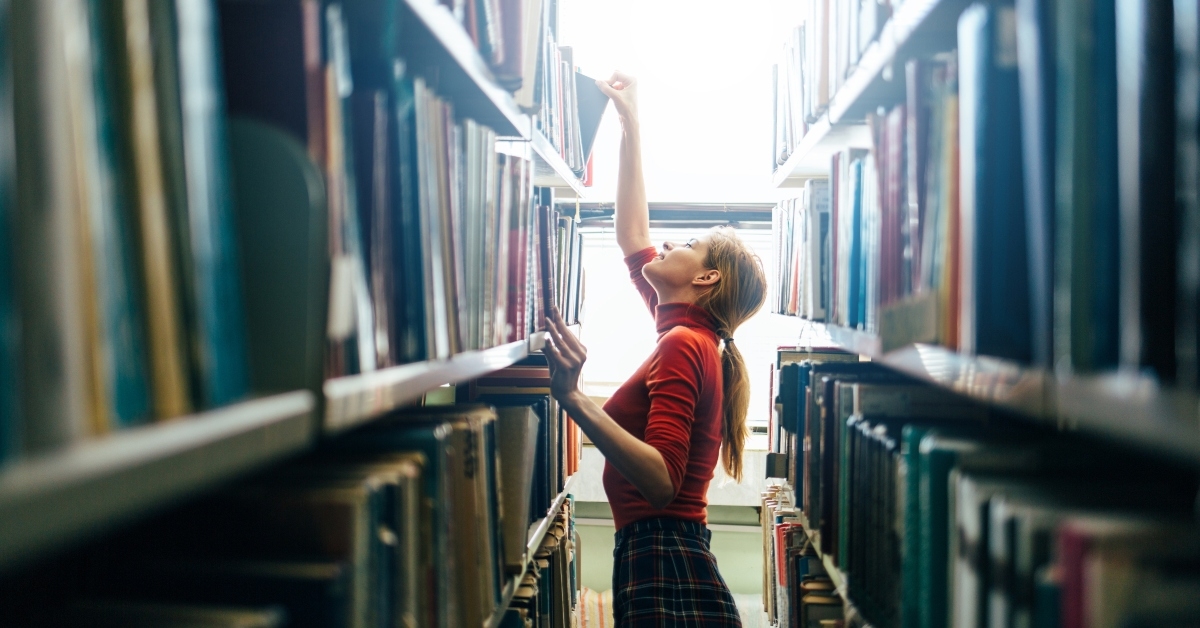 librarian taking one book from library bookshelf