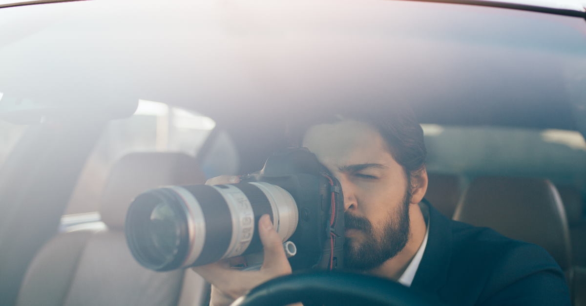 male detective sitting in car capturing pictures 