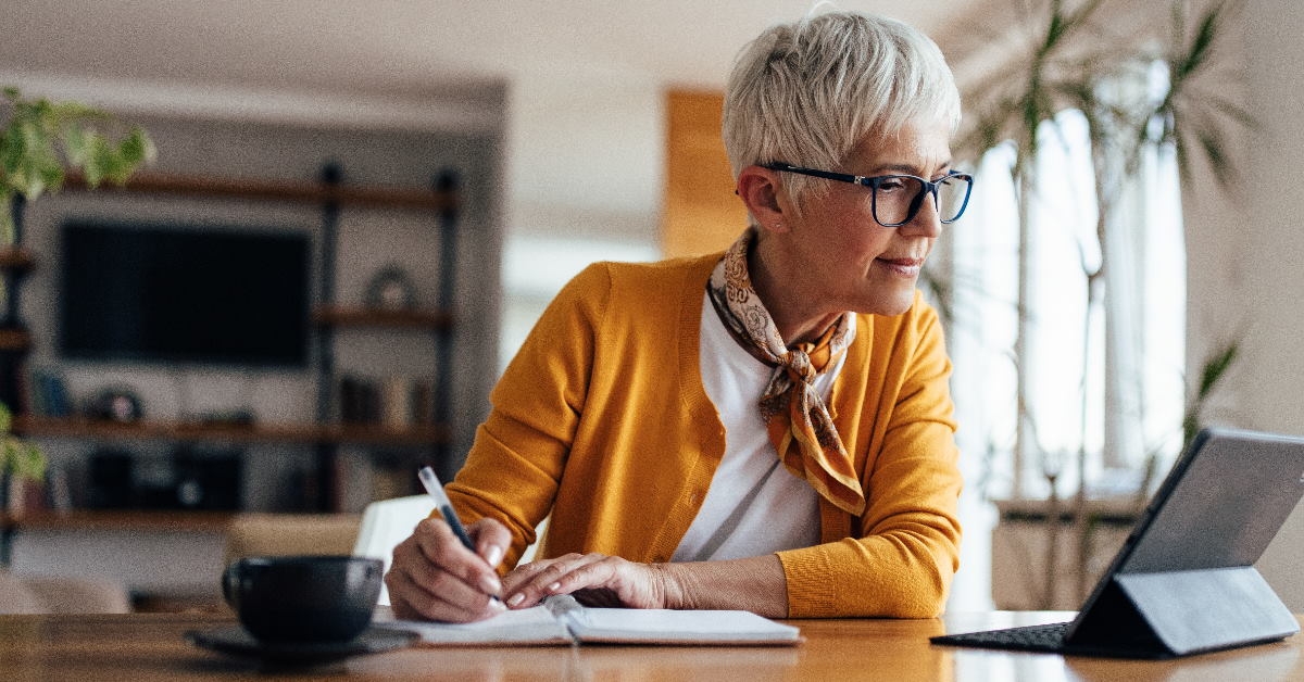 senior business woman working from home writing on notebook 