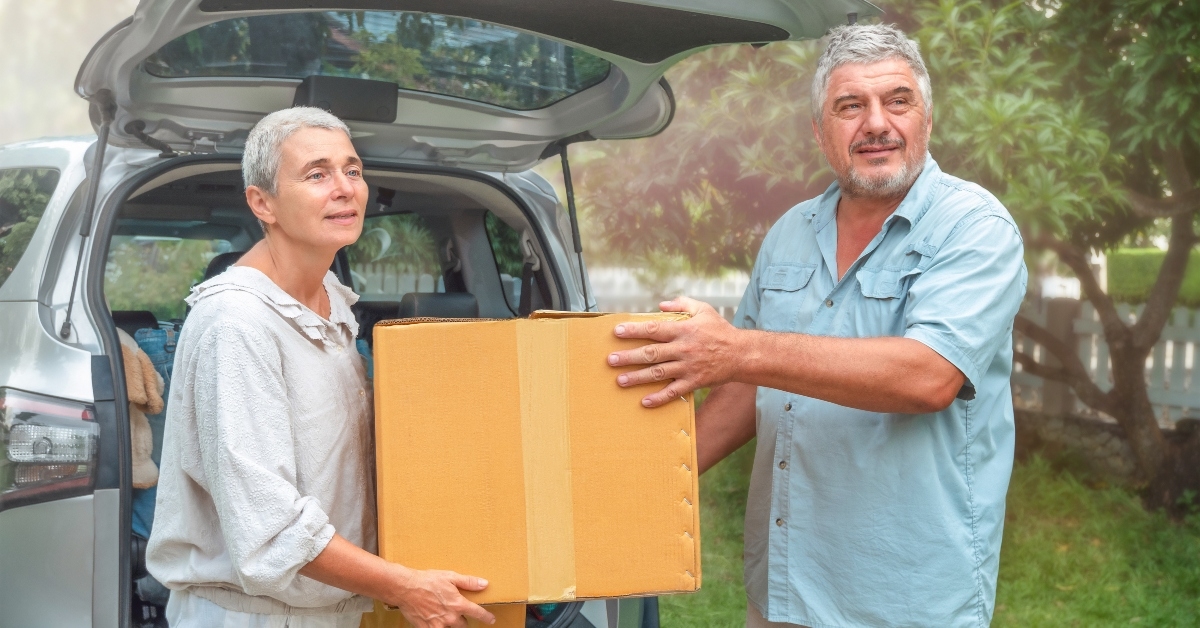 senior couple carry box from car