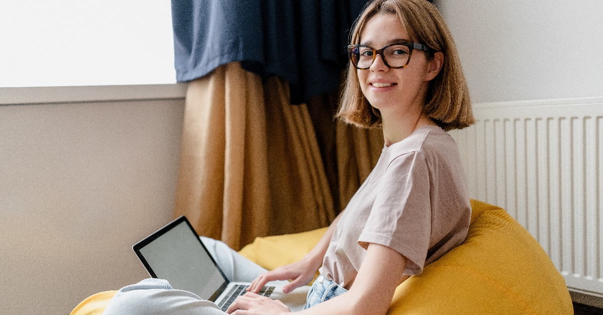 woman working from home using laptop while sitting on yellow bean bag