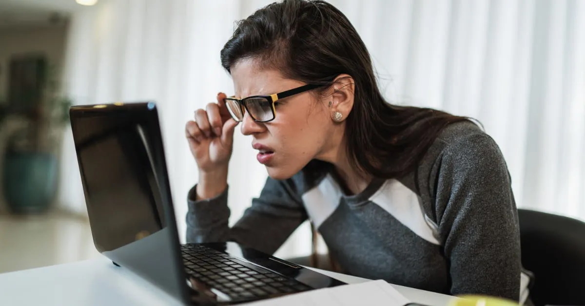 woman with visual impairment struggling to read the content on her laptop