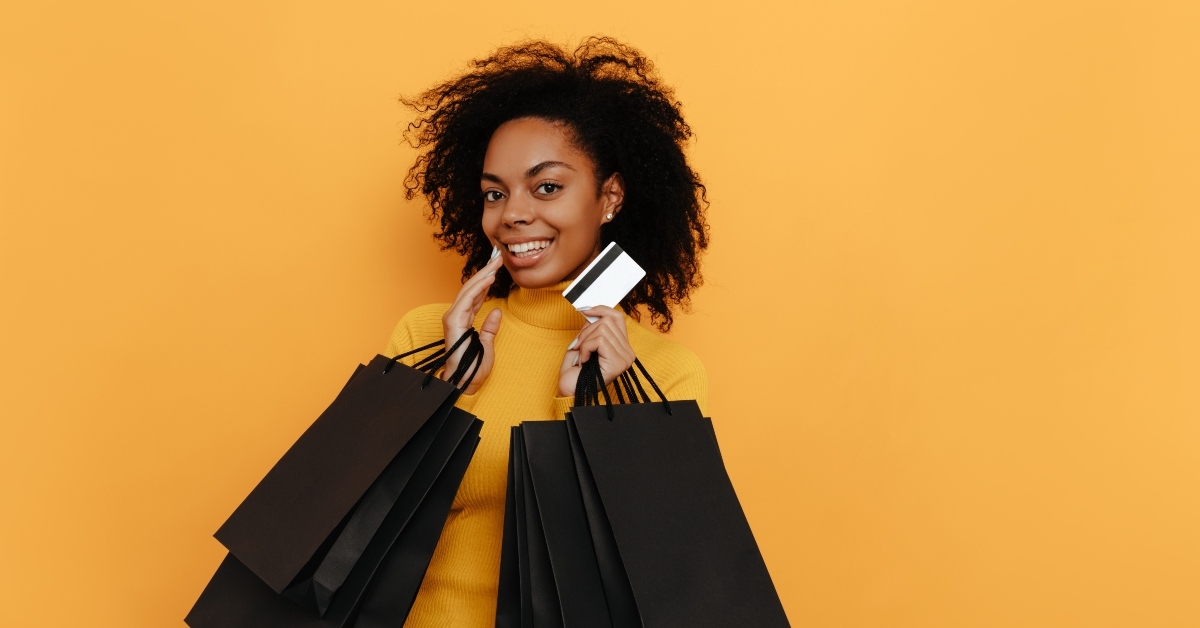  girl in yellow sweater is holding shopping bags and a credit card