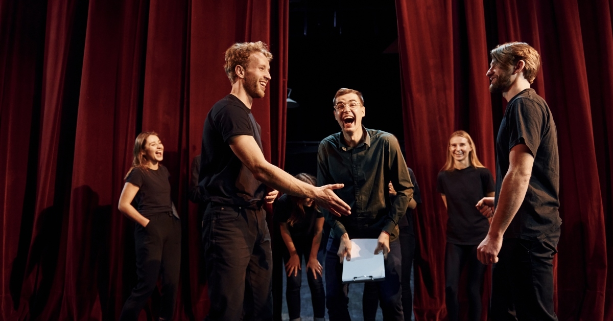 group of actors in dark colored clothes on rehearsal