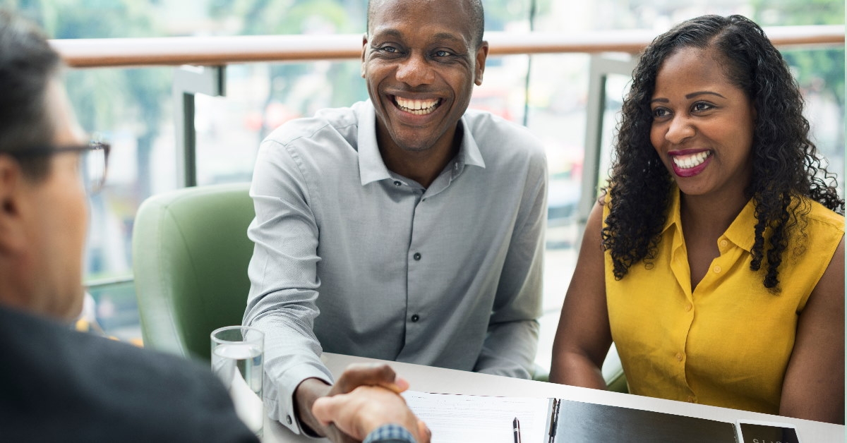happy couple shaking hands with real estate agent 