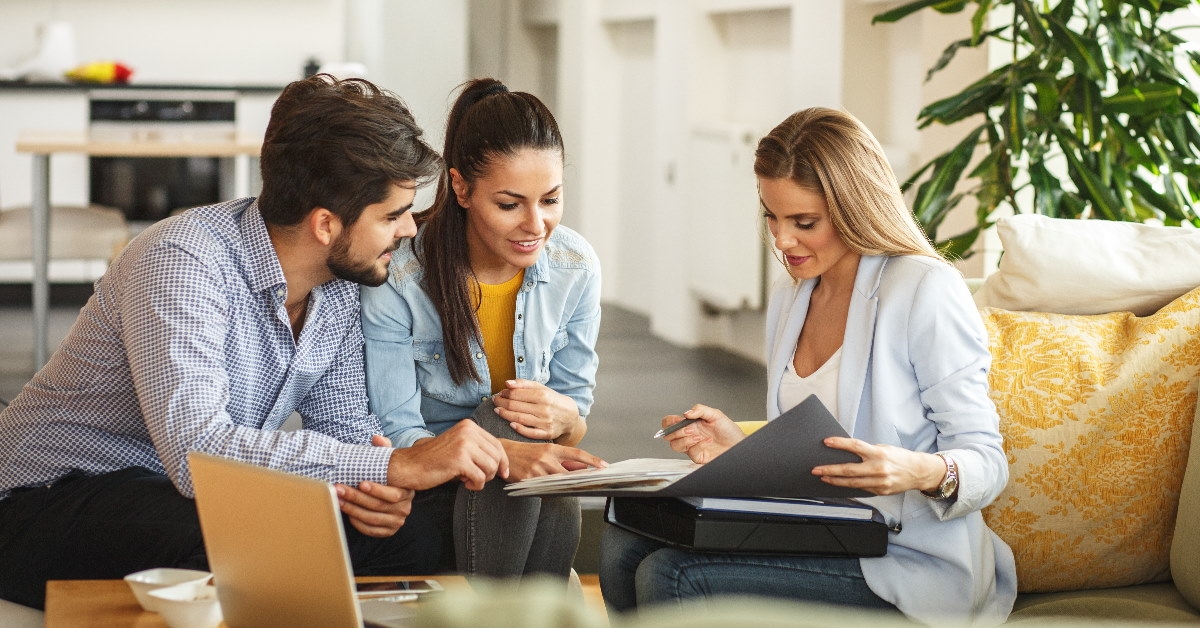 young couple sitting with real estate advisor explaining ideas
