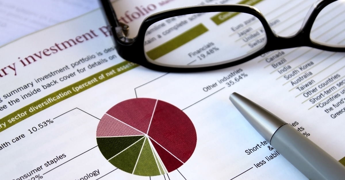 glasses and pen on financial portfolio with graphs 