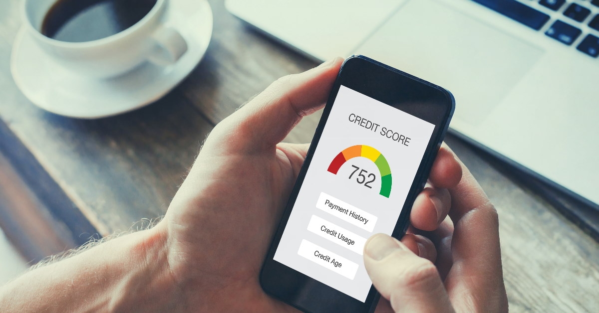 woman sitting in front of laptop at table reviewing documents in hand