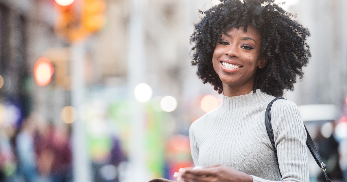 pretty african american woman standing in street wearing white turtleneck