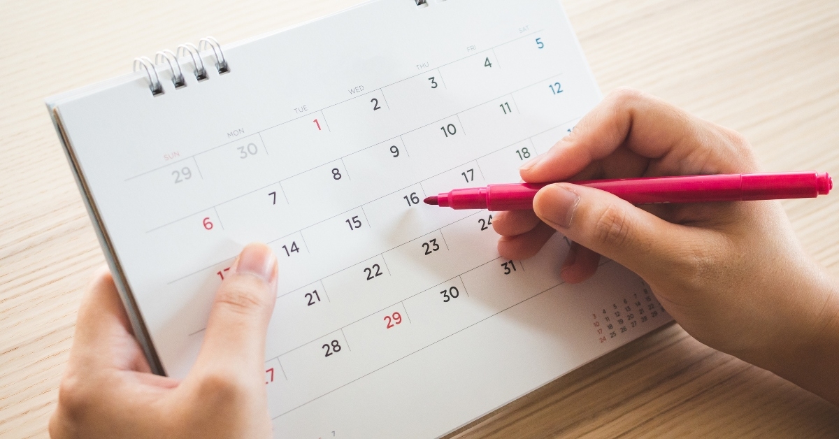 hand with pen writing on calendar page
