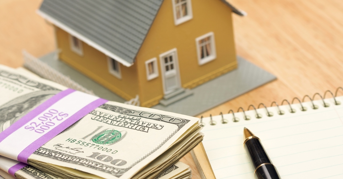 house and money with pad of paper and pen
