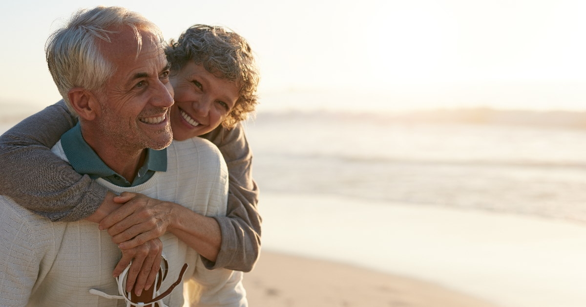 couple having each other back while smiling at beach