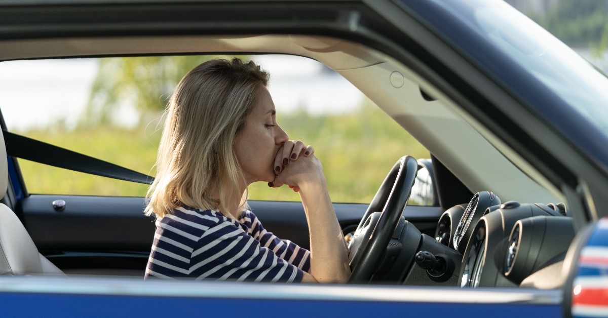 frustrated female sit inside car at driver seat putting chin on hands