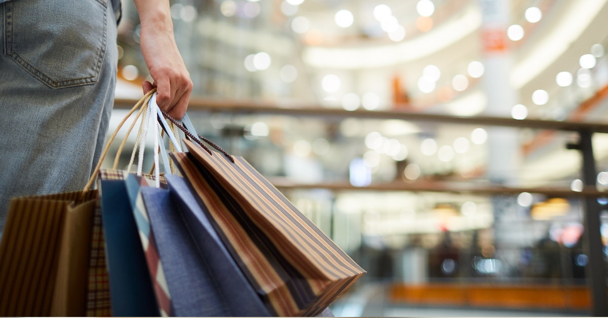woman standing at mall holding shopping bags in hand