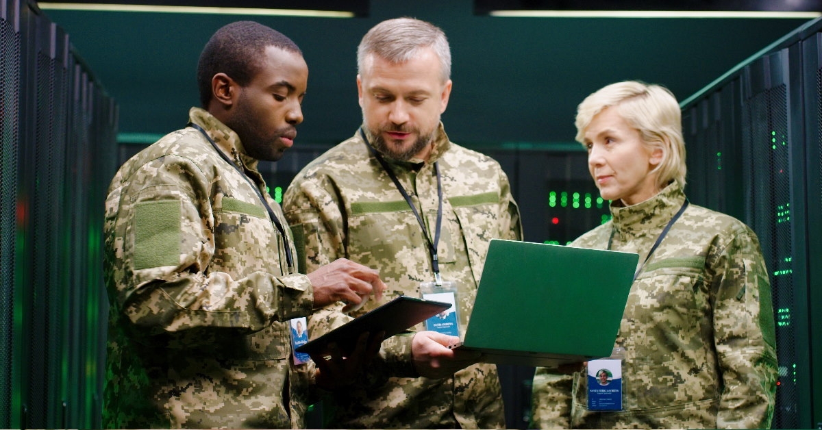 multiethnic male and female army officers discussing work on laptop and tablet at analytic centre