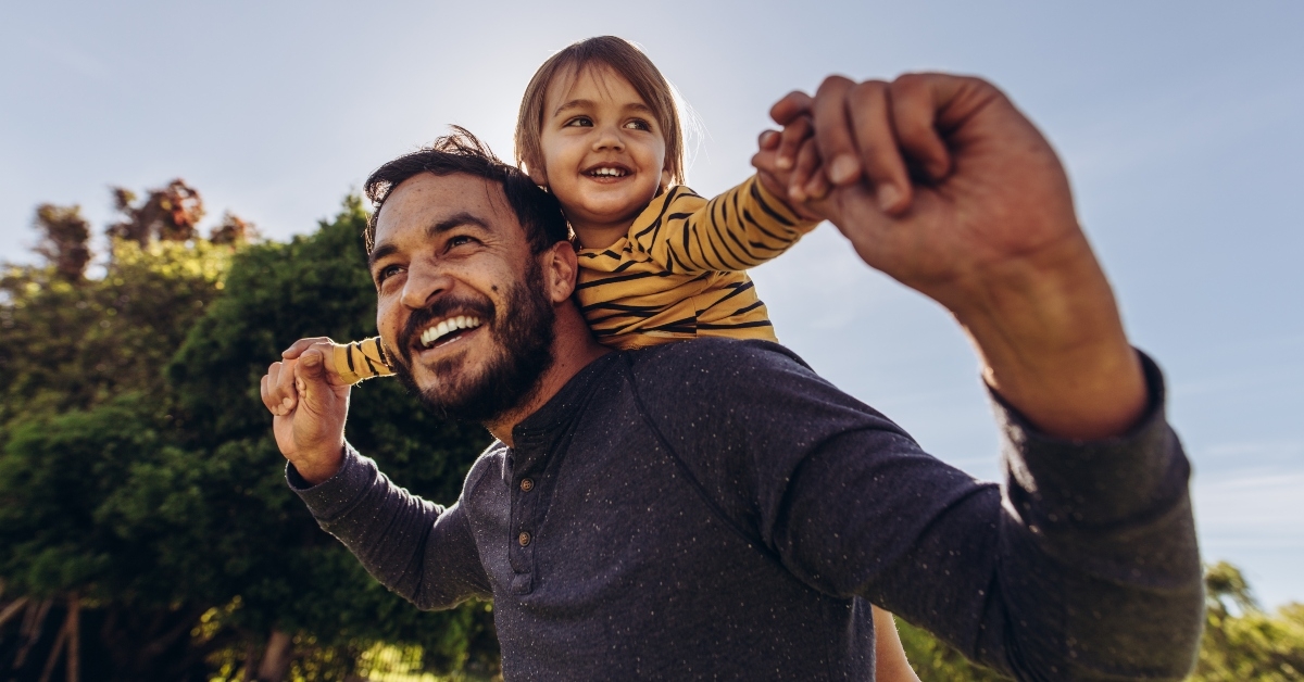 smiling man playing with his kid outdoors