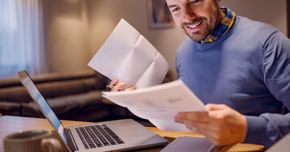 young smiling man holding bills in his hands and calculating payment