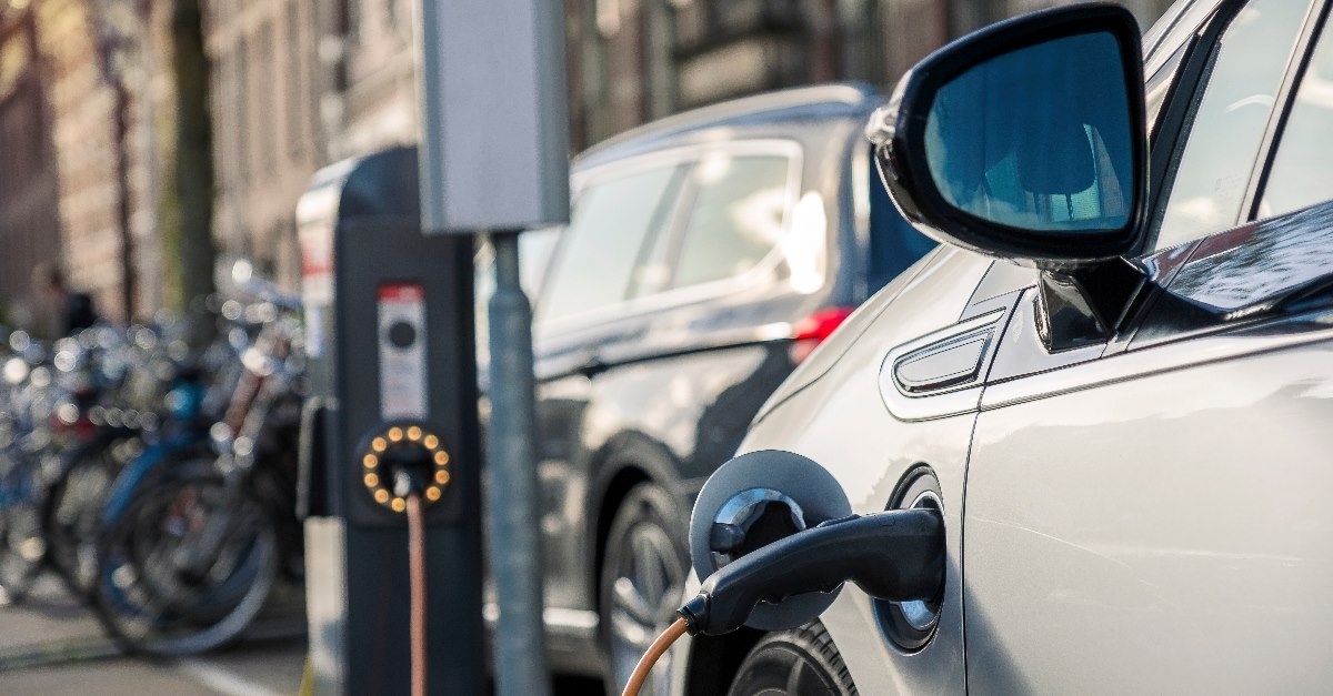 electric car in street connected with electric source for charge during day time