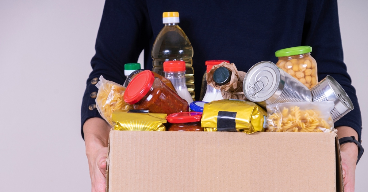 volunteer hands holding food donations box with groceries