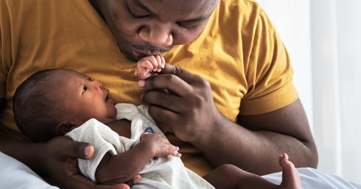 father kissing hand of newborn son
