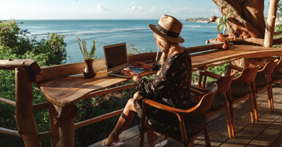  young woman using laptop in cafe on tropical beach 